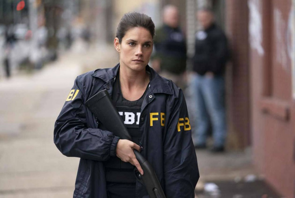 Maggie Bell (Missy Peregrym) arme à la main s'apprête à rentrer dans un bâtiment.